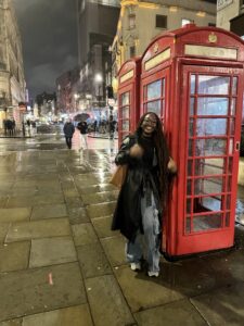 Kendrah standing next to a red British telephone booth.