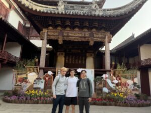 Abzal and 2 friends, posing in front of a historical Chinese style building.